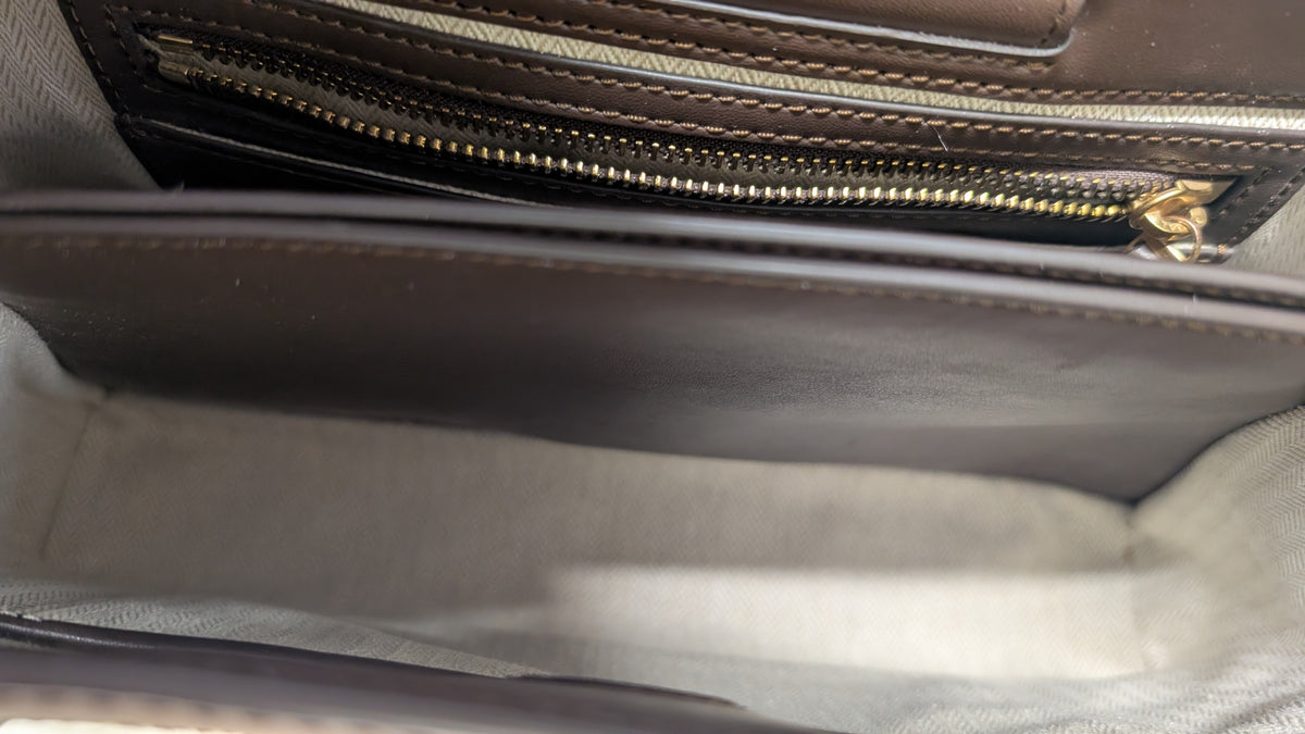 Close-up of the interior of a dark brown leather handbag, showing a gold zipper track and a light gray fabric lining. Pre-Owned Tory Burch  Floral Applique Top Handle Bag