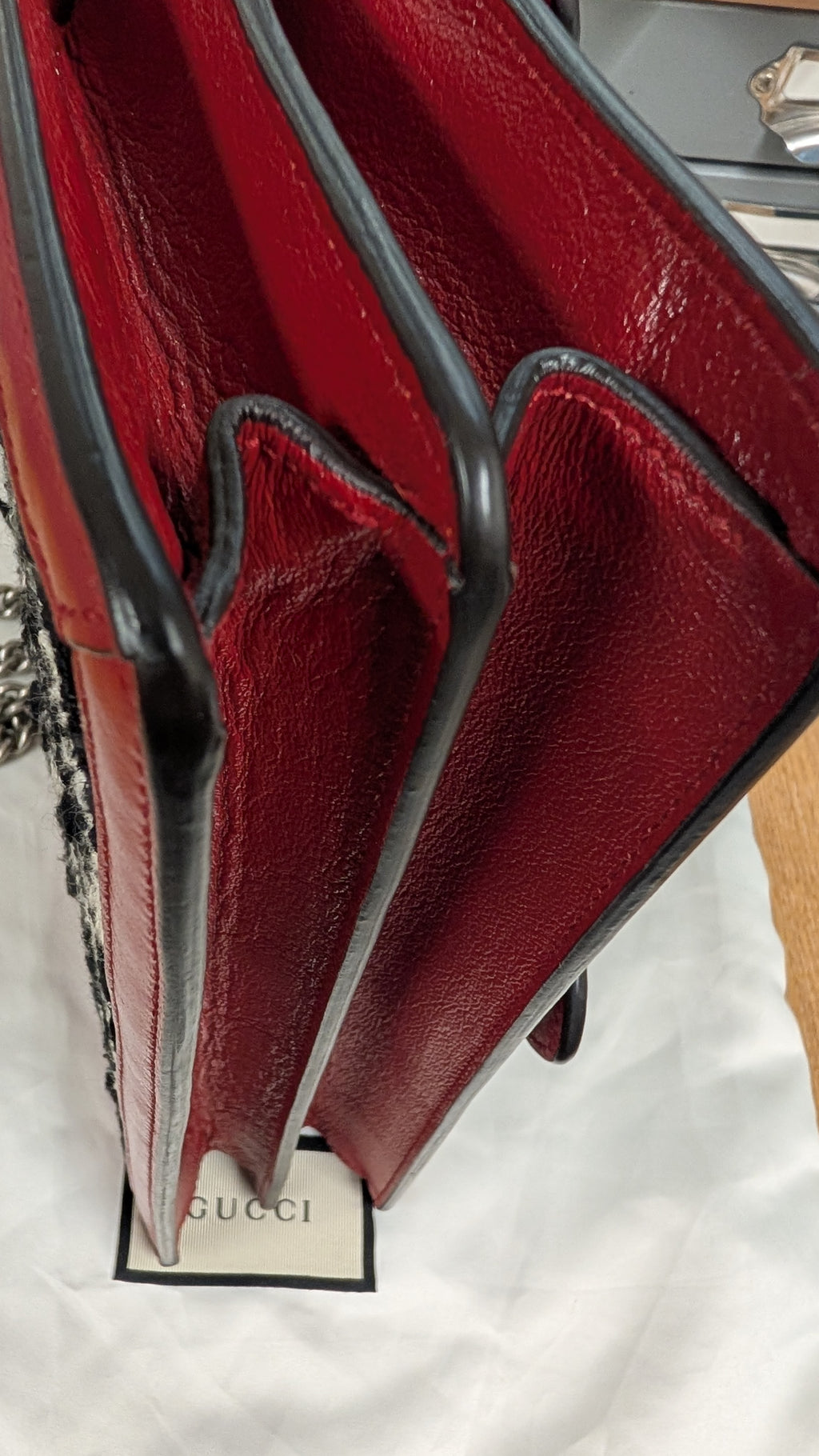 Close-up of a red leather handbag showing the interior lining, black trim, and a Gucci tag on white fabric. Pre-Owned Gucci Dionysus GG Tweed Medium Shoulder Bag – Red/Black