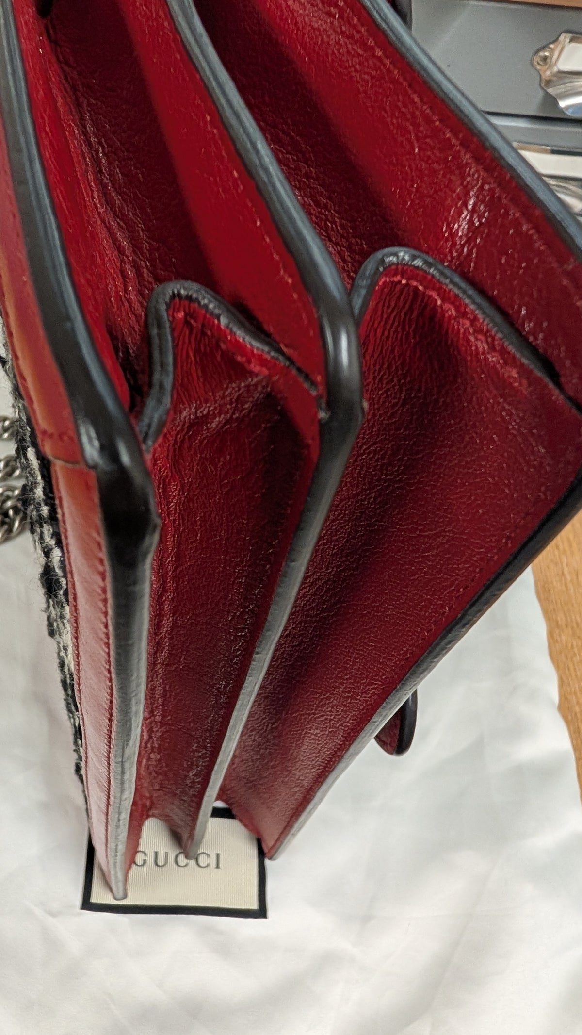 Close-up of a red leather handbag showing the interior lining, black trim, and a Gucci tag on white fabric. Pre-Owned Gucci Dionysus GG Tweed Medium Shoulder Bag – Red/Black