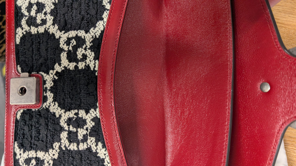 Close-up of a red leather clutch or wallet showing the interior flap, a silver snap button, and a black and beige monogram patterned fabric panel. Pre-Owned Gucci Dionysus GG Tweed Medium Shoulder Bag – Red/Black