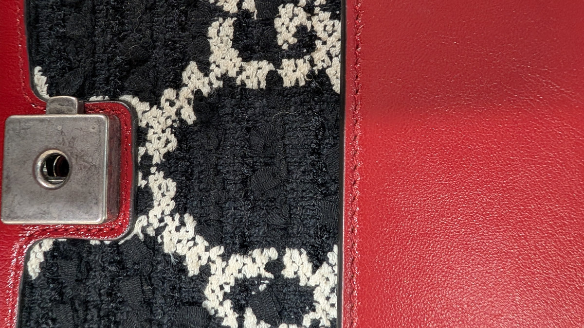 Close-up of a red leather accessory with a black and white patterned woven panel and a silver metal clasp. Pre-Owned Gucci Dionysus GG Tweed Medium Shoulder Bag – Red/Black