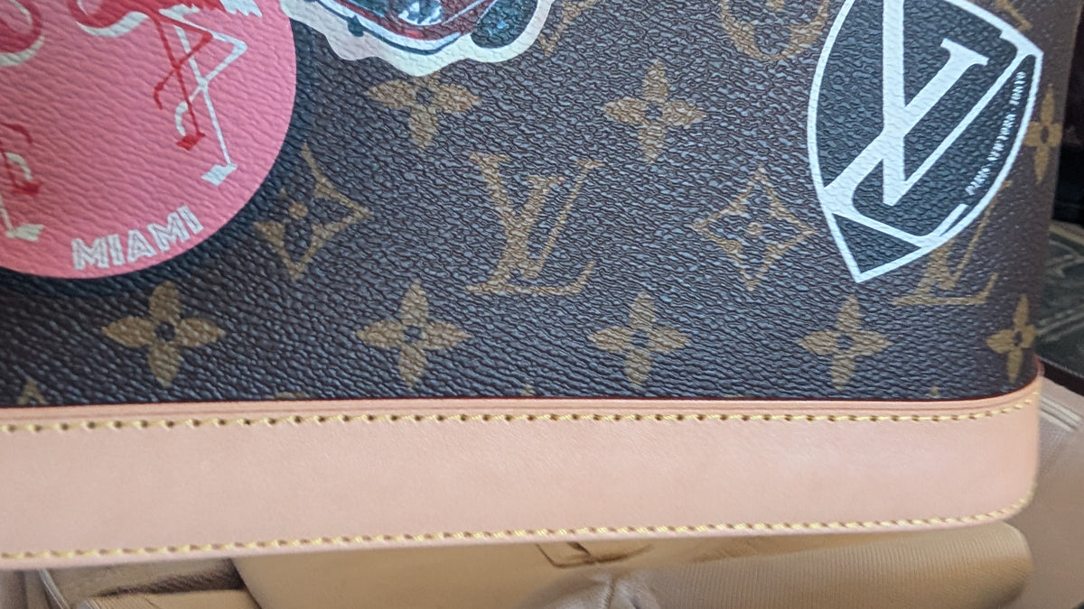 Close-up of a Louis Vuitton monogram canvas bag with a beige leather trim and decorative patches, including a pink 'MIAMI' patch and a white LV shield patch.