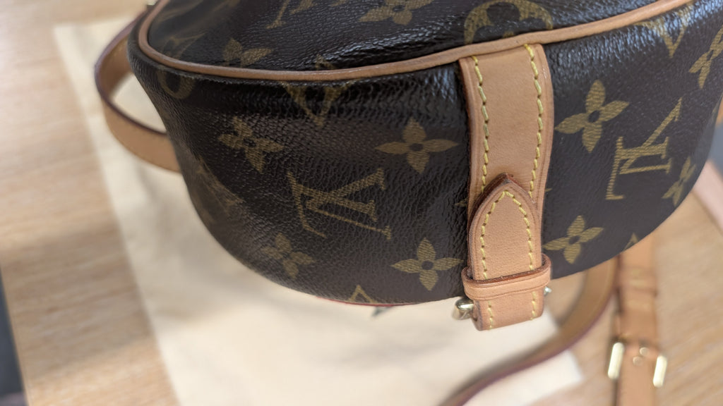 Close-up of a Louis Vuitton monogram bag in dark brown coated canvas with tan leather trim and strap, resting on a light surface. Pre-Owned Louis Vuitton Monogram Tambourin Shoulder / Crossbody Bag