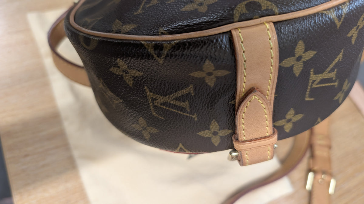 Close-up of a Louis Vuitton monogram bag in dark brown coated canvas with tan leather trim and strap, resting on a light surface. Pre-Owned Louis Vuitton Monogram Tambourin Shoulder / Crossbody Bag