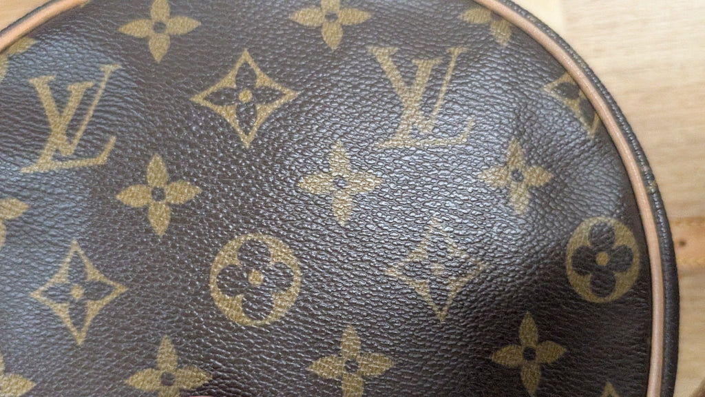 A close-up of a Louis Vuitton monogram canvas bag, showing the classic brown and tan pattern. A finger is pointing at the bag's texture. Pre-Owned Louis Vuitton Monogram Tambourin Shoulder / Crossbody Bag