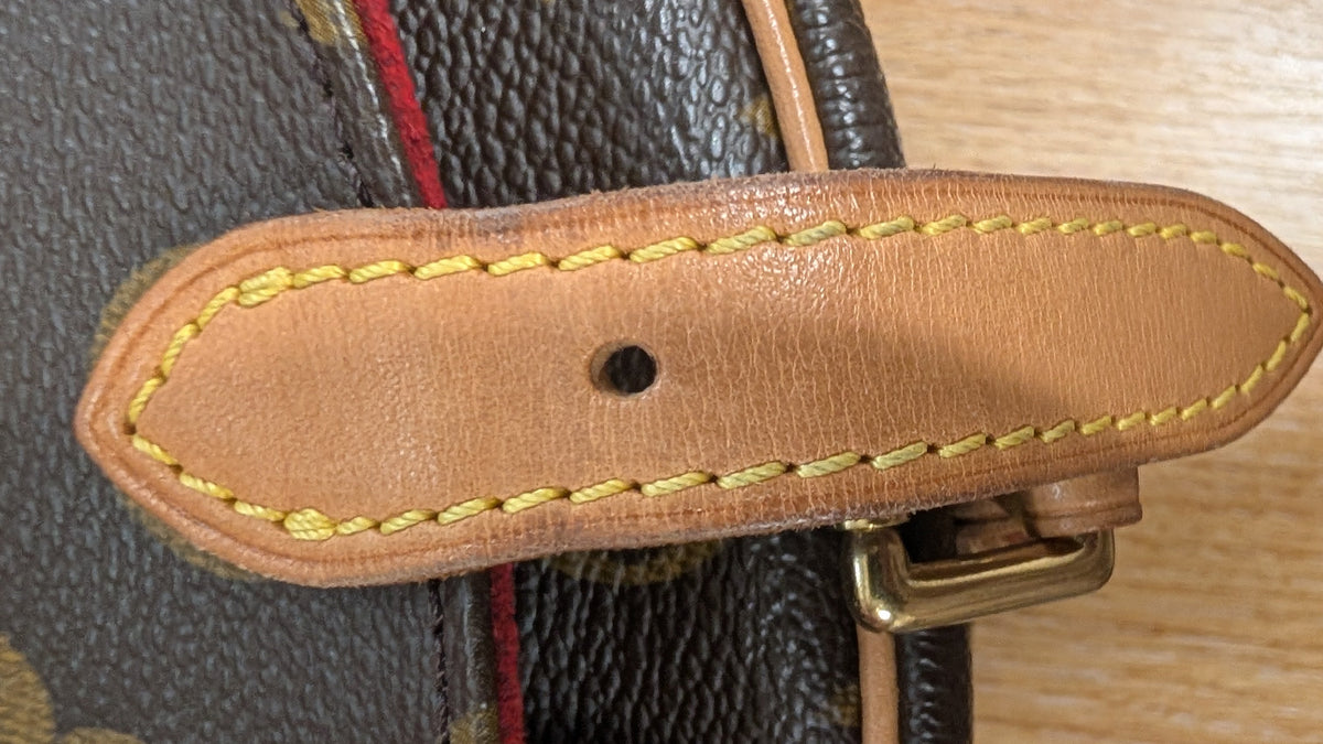 Close-up of a brown monogram handbag strap with tan leather trim and yellow stitching, attached to a gold-tone metal buckle.   Pre-Owned Louis Vuitton Monogram Tambourin Shoulder / Crossbody Bag