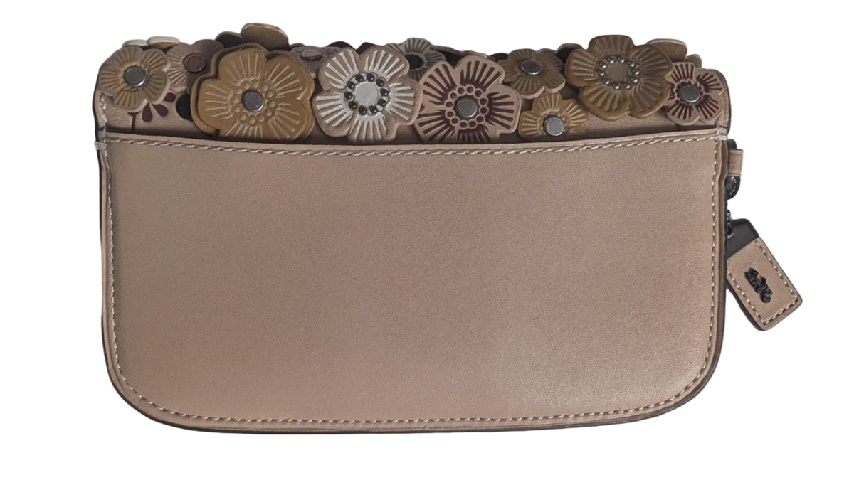 A beige leather zip-around wallet with a decorative border of 3D floral embellishments on the left side, photographed on a white fabric background. Pre-Owned Coach Courier Wristlet with Floral Appliqué – Glovetanned Leather