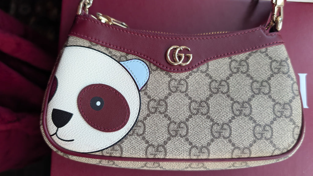 A Gucci shoulder bag featuring the brand's classic GG Supreme canvas, a burgundy leather trim and strap, and a large embroidered panda face on the front. The iconic interlocking GG logo is visible in gold-tone metal on the front flap. Pre-Owned Gucci GG Supreme Ophidia Panda Mini Chain Shoulder Bag