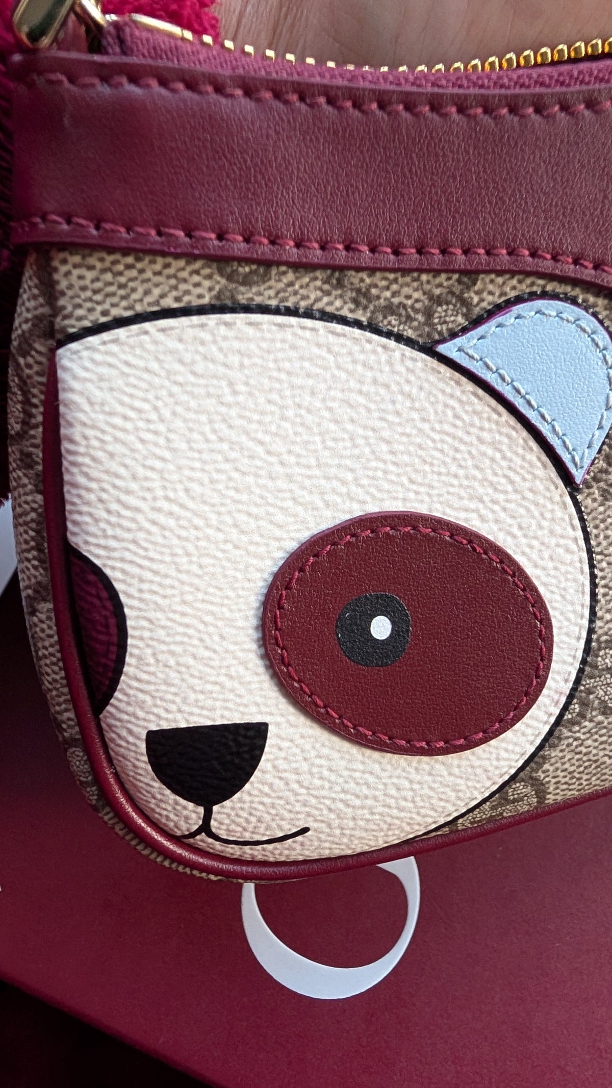 Close-up of a small handbag or pouch with a panda face applique on a beige monogram canvas background, featuring burgundy leather trim and a gold zipper. Pre-Owned Gucci GG Supreme Ophidia Panda Mini Chain Shoulder Bag