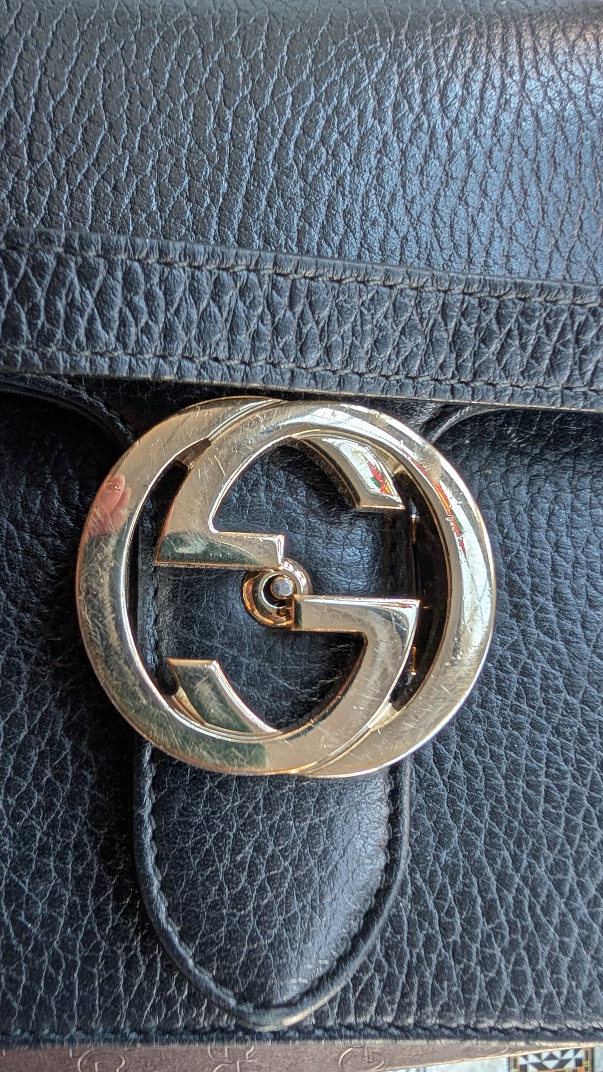 Close-up of a black pebbled leather handbag featuring a large polished gold-tone interlocking G logo clasp, with the Gucci brand represented by the iconic logo. Pre-Owned Gucci Interlocking Black shoulder bag 