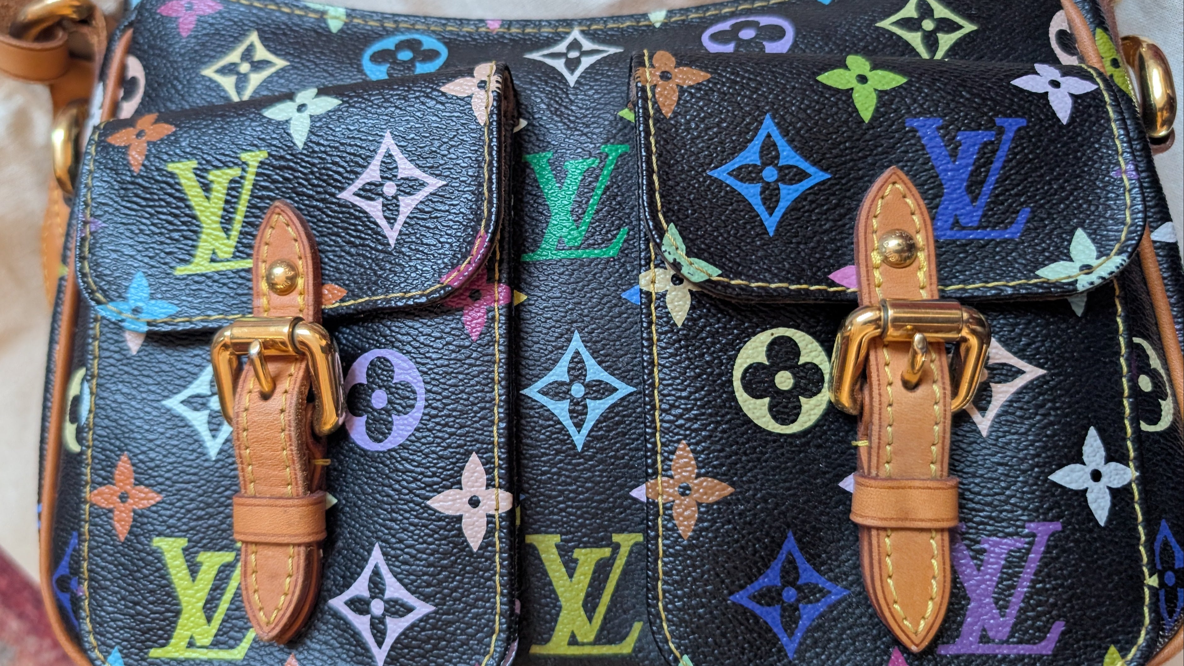 Close-up of a Louis Vuitton monogram handbag in black coated canvas with colorful printed motifs and tan leather straps and buckles. Pre-Owned Louis Vuitton Takashi Murakami Lodge PM Shoulder Bag