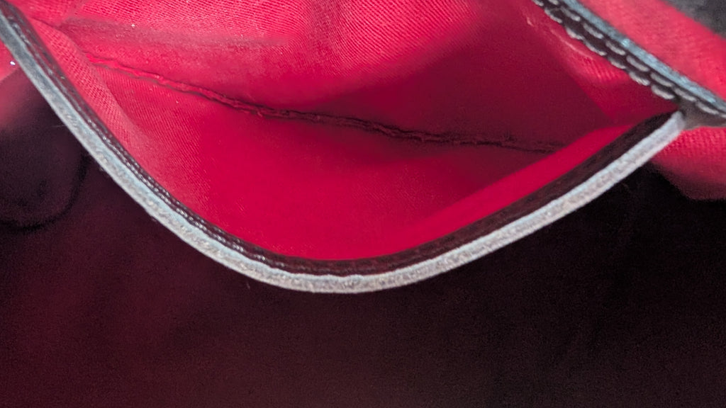 Close-up of the interior lining of a red bag or pouch, showing a bright red fabric interior with a stitched edge and a dark gray or black outer trim. Pre-Owned Louis Vuitton Speedy 25 in classic Damier Ebene coated canvas