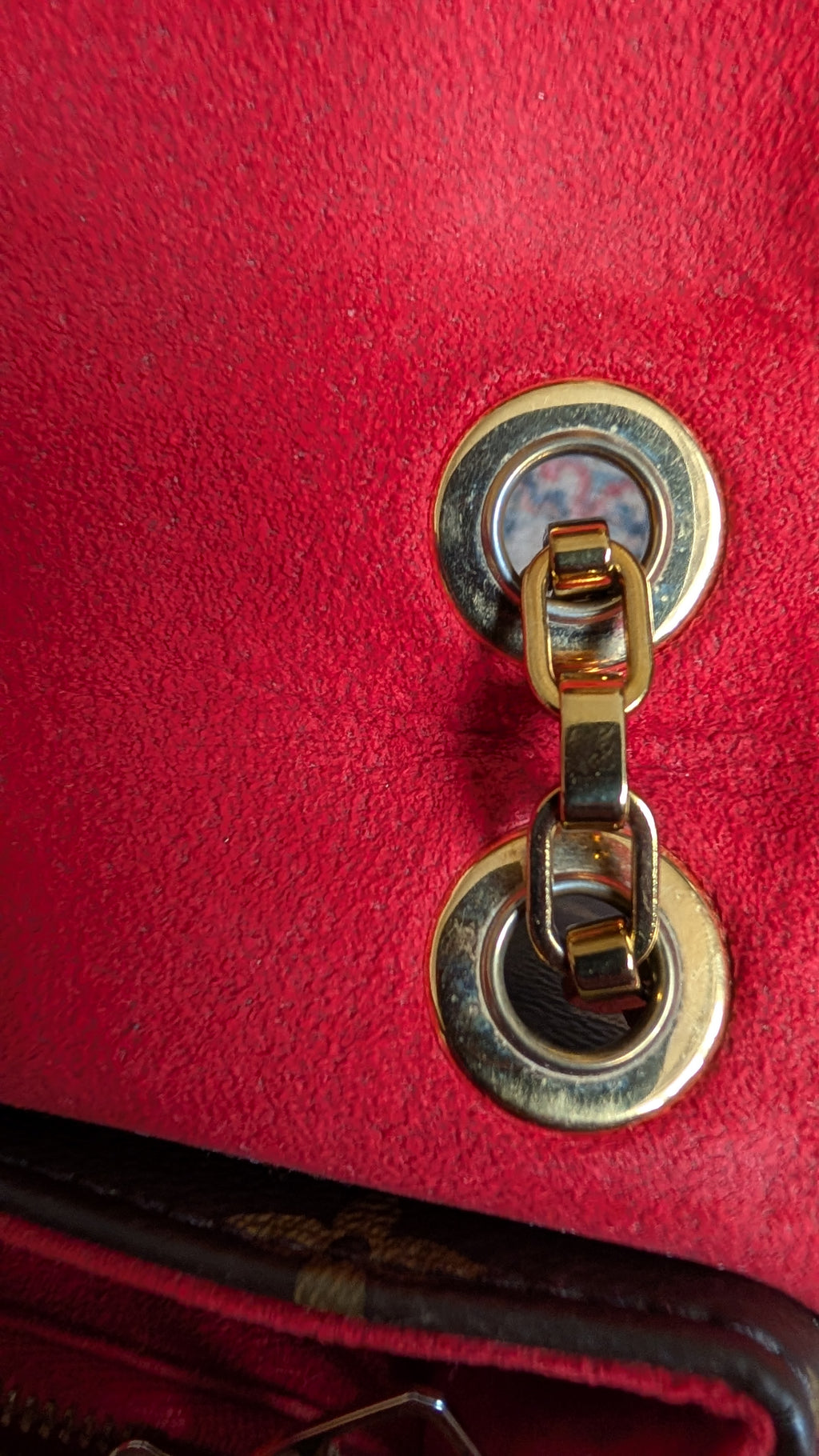 Close-up of a red textured handbag featuring a gold-tone metal turn-lock clasp with a chain link. Pre-Owned Louis Vuitton Pallas Chain Monogram Canvas Shoulder Bag – Cerise Red – M41201