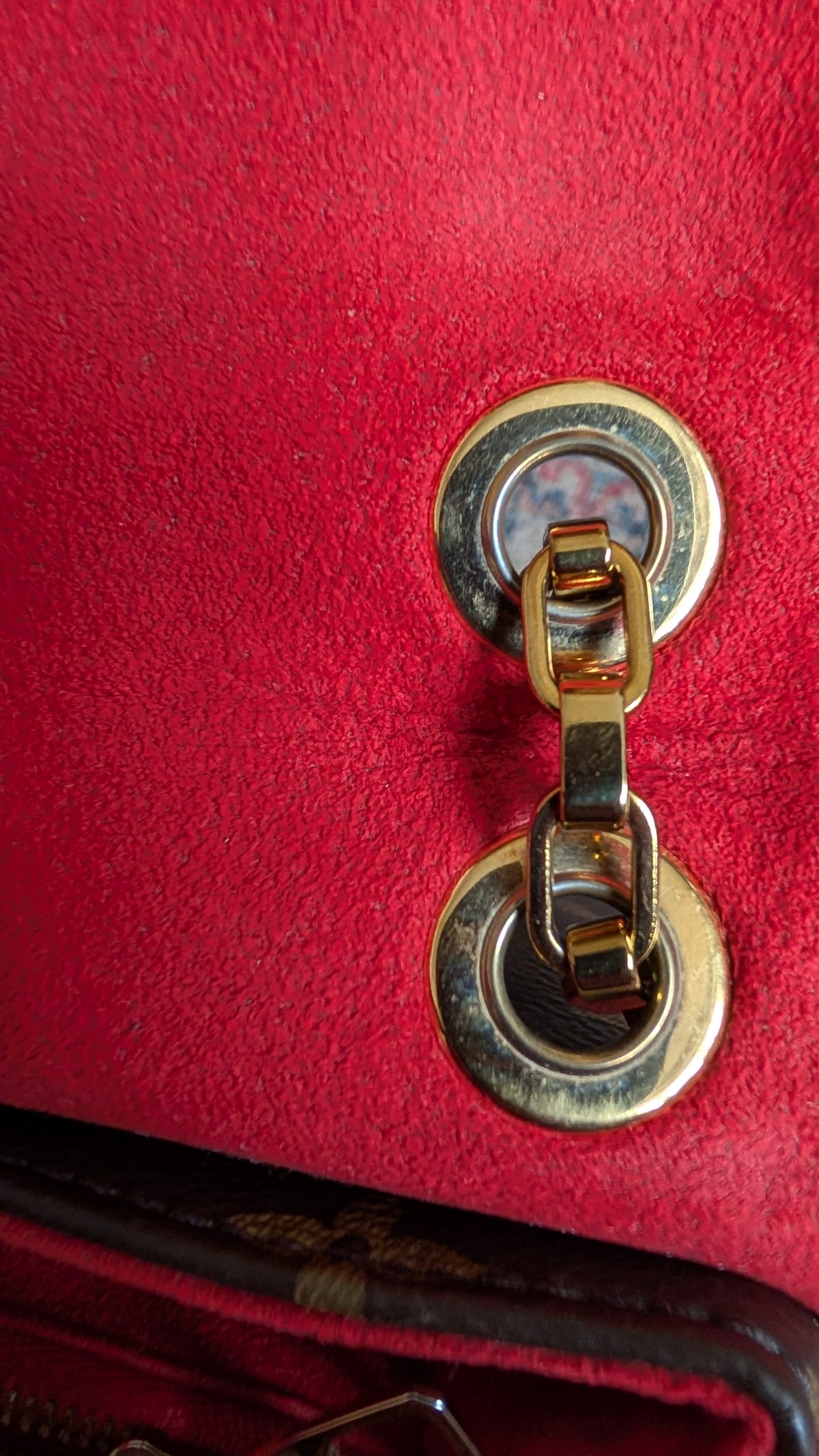 Close-up of a red textured handbag featuring a gold-tone metal turn-lock clasp with a chain link. Pre-Owned Louis Vuitton Pallas Chain Monogram Canvas Shoulder Bag – Cerise Red – M41201