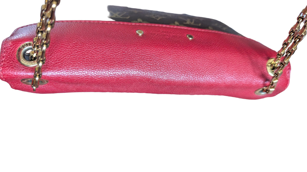 A close-up of a Louis Vuitton shoulder bag in red pebbled leather with gold-tone hardware, shown resting on a patterned red and blue rug. Pre-Owned Louis Vuitton Pallas Chain Monogram Canvas Shoulder Bag – Cerise Red – M41201