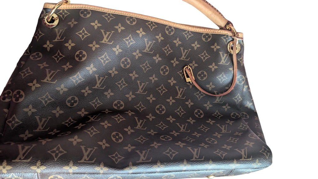 A Louis Vuitton monogram canvas tote bag in dark brown and tan, resting on a patterned red and blue rug. Pre-Owned Louis Vuitton Artsy MM Monogram Canvas Shoulder Bag 