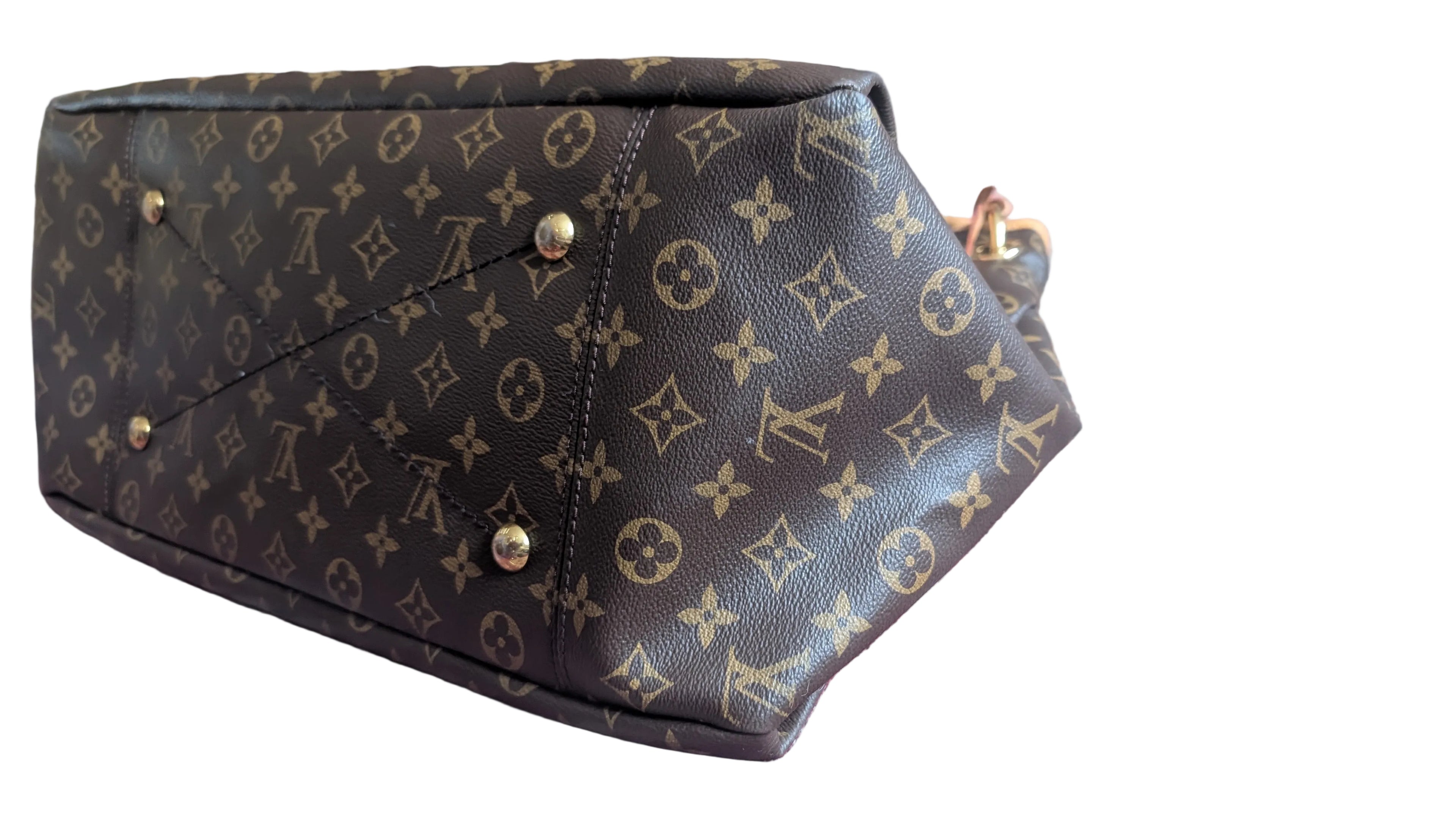 A Louis Vuitton monogram canvas handbag shown from an angled bottom view, resting on a patterned red and blue rug. The dark brown coated canvas features the classic tan monogram pattern with gold-tone metal studs and hardware. Pre-Owned Louis Vuitton Artsy MM Monogram Canvas Shoulder Bag 