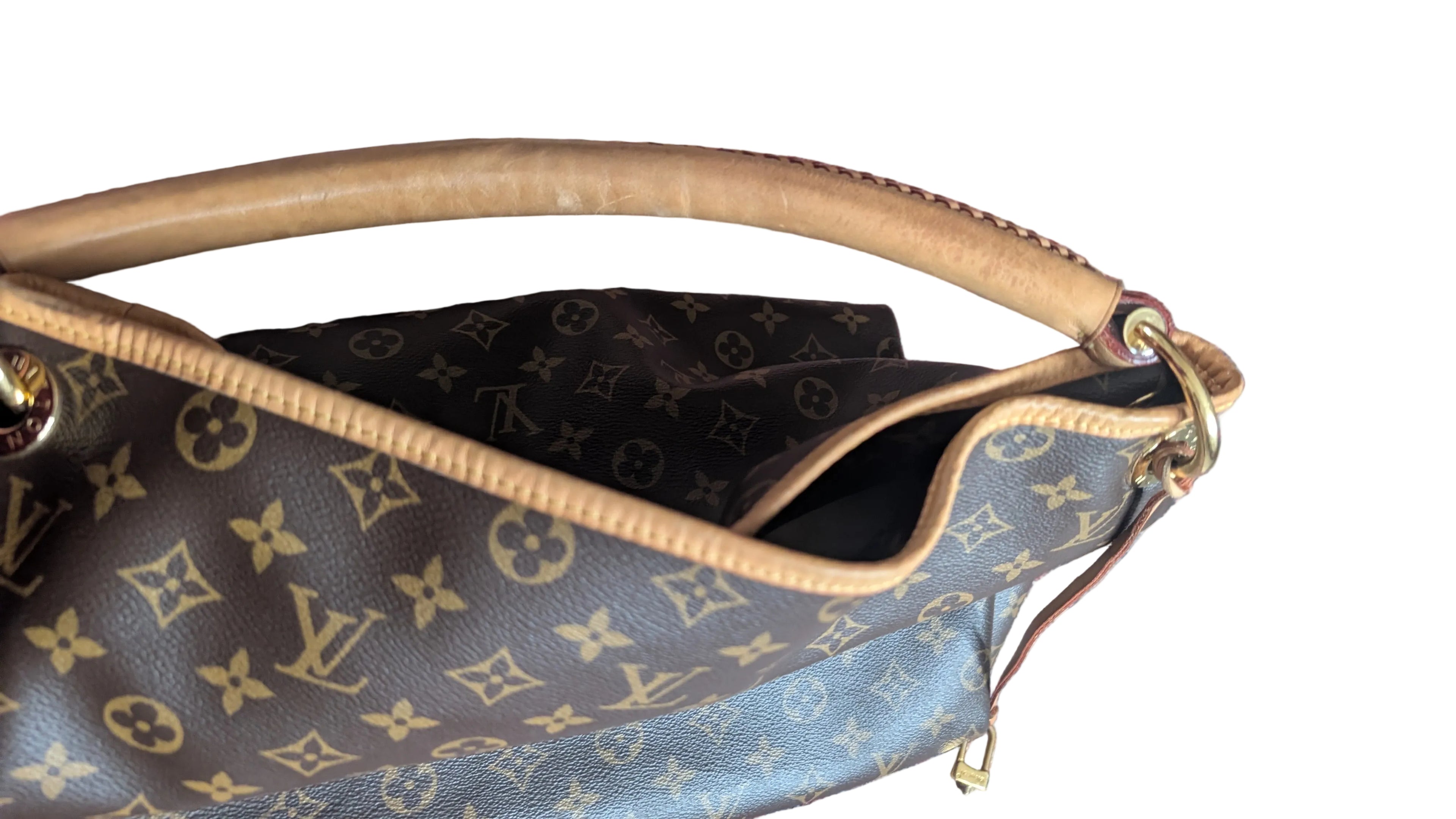 A close-up of a Louis Vuitton monogram handbag with a tan leather handle, shown resting on a patterned red and blue rug. Pre-Owned Louis Vuitton Artsy MM Monogram Canvas Shoulder Bag 