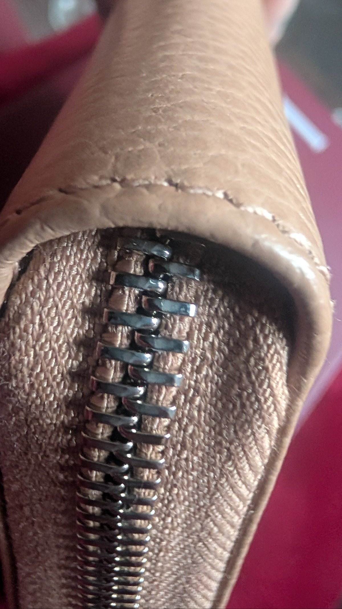 Close-up of a tan textured leather zippered pouch or wallet, showing the zipper and interior lining. Pre-Owned Gucci Interlocking G Zip-Around Continental Purse in Nude/Taupe Leather