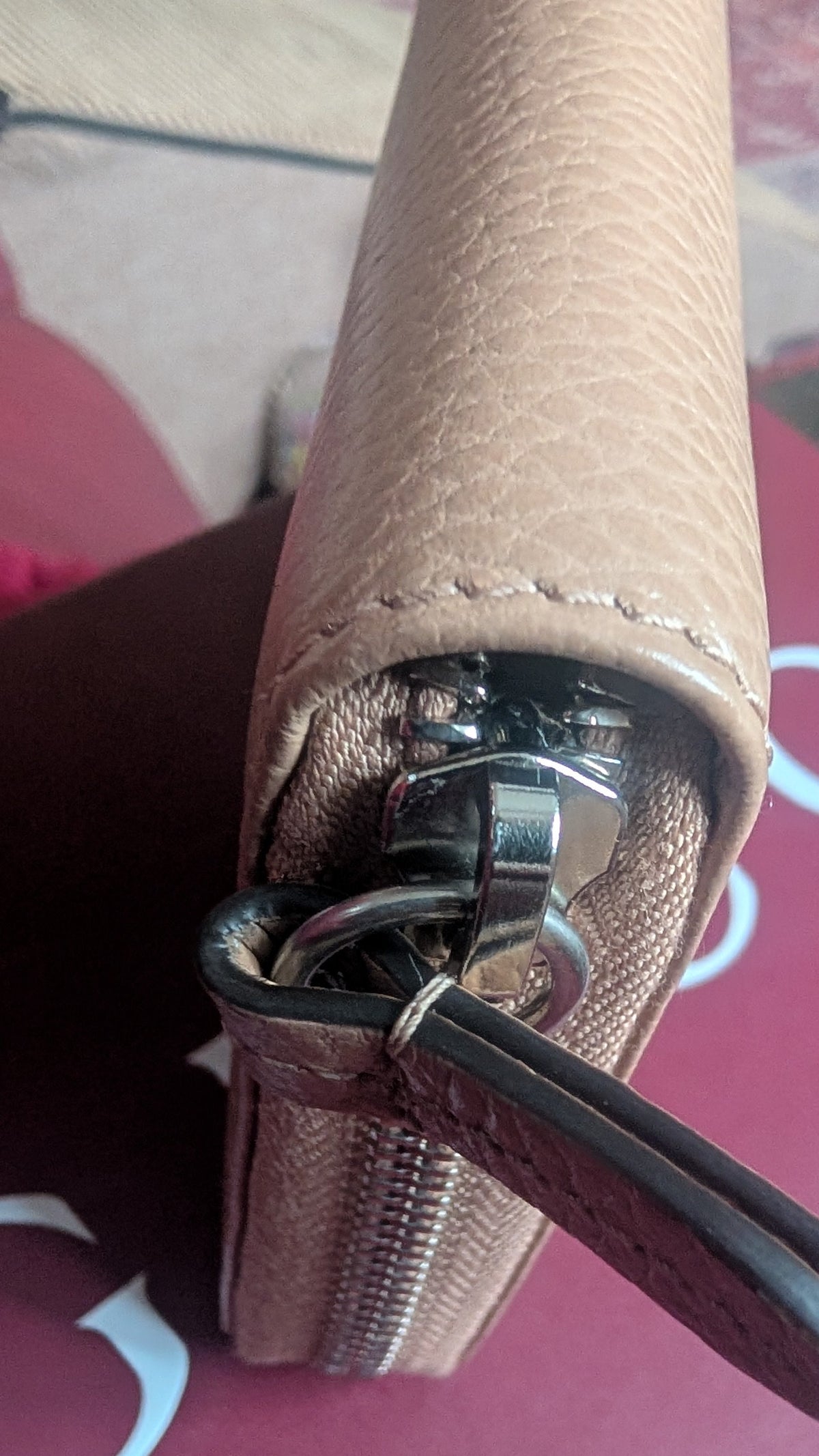 A close-up of a beige pebbled leather wallet or clutch with a silver-tone zipper and a dark leather pull tab, resting on a burgundy Gucci box. Pre-Owned Gucci Interlocking G Zip-Around Continental Purse in Nude/Taupe Leather