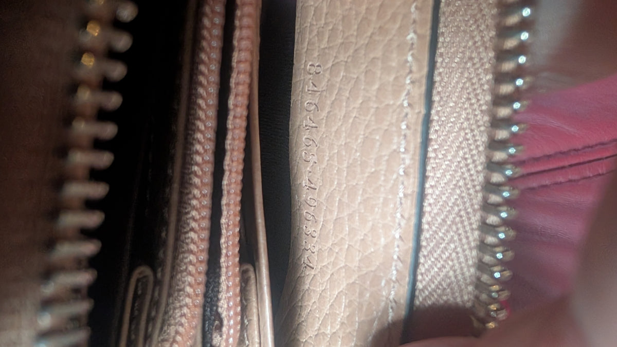 Close-up of a beige pebbled leather wallet interior with silver-toned zippers and a textured canvas side panel. Pre-Owned Gucci Interlocking G Zip-Around Continental Purse in Nude/Taupe Leather