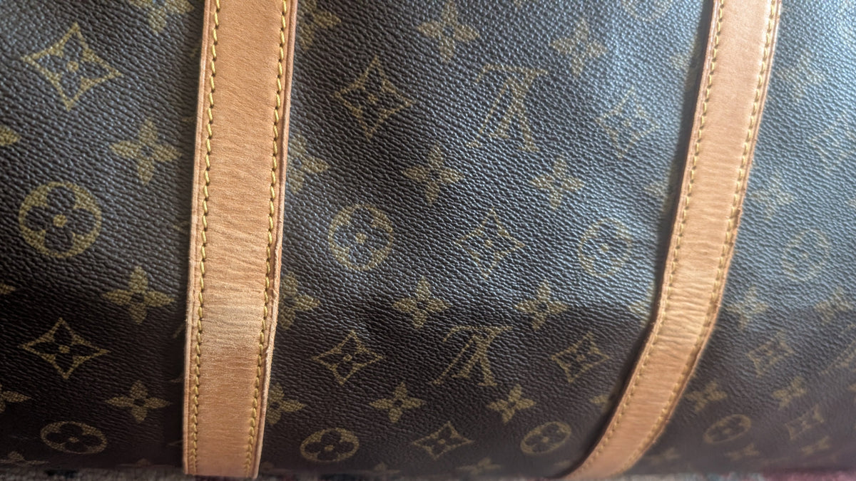 Close-up of a Louis Vuitton monogram canvas bag with tan leather trim, showing the classic dark brown and beige pattern. Pre-Owned Louis Vuitton Keepall Bandoulière 60 Monogram Travel Bag