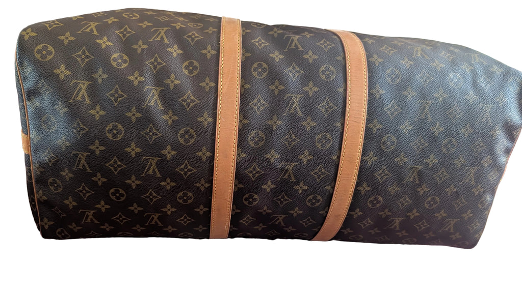 A Louis Vuitton monogram canvas duffel bag with tan leather trim, resting on a patterned red and blue rug. Pre-Owned Louis Vuitton Keepall Bandoulière 60 Monogram Travel Bag