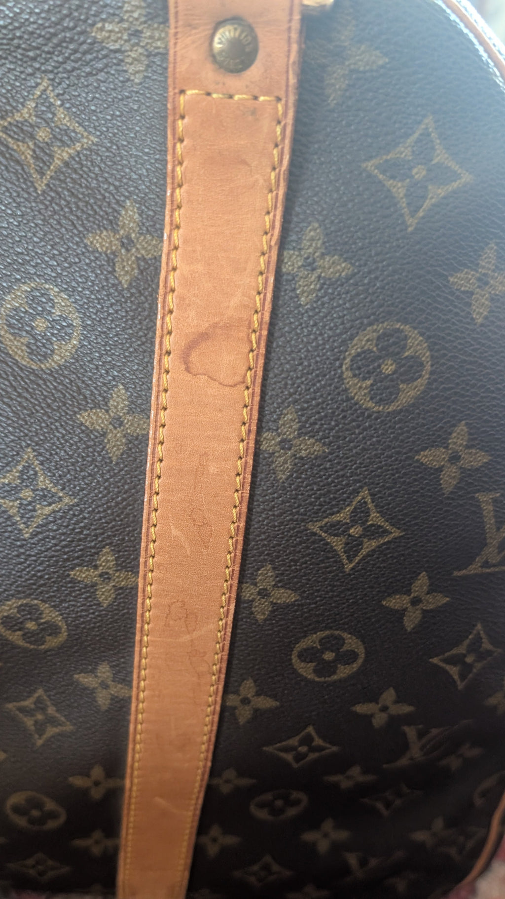 Close-up of a Louis Vuitton monogram duffel bag in dark brown coated canvas with tan leather trim, resting on a patterned rug. Pre-Owned Louis Vuitton Keepall Bandoulière 60 Monogram Travel Bag
