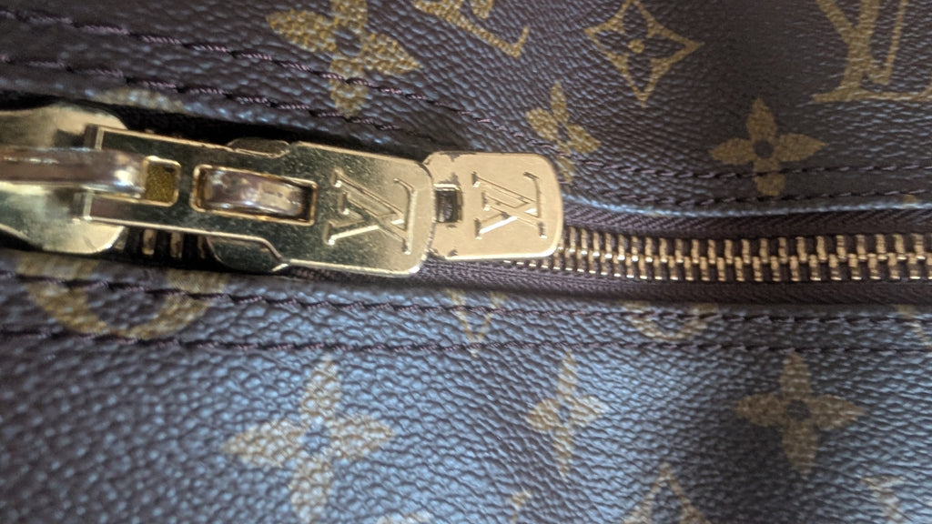 Close-up of a Louis Vuitton monogram bag with a gold-tone metal zipper pull and zipper track on dark brown coated canvas. Pre-Owned Louis Vuitton Keepall Bandoulière 60 Monogram Travel Bag