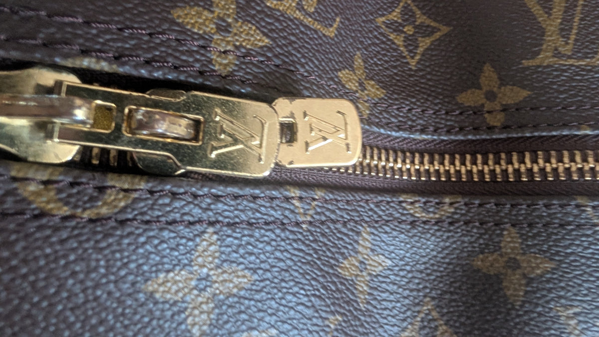 Close-up of a Louis Vuitton monogram bag with a gold-tone metal zipper pull and zipper track on dark brown coated canvas. Pre-Owned Louis Vuitton Keepall Bandoulière 60 Monogram Travel Bag