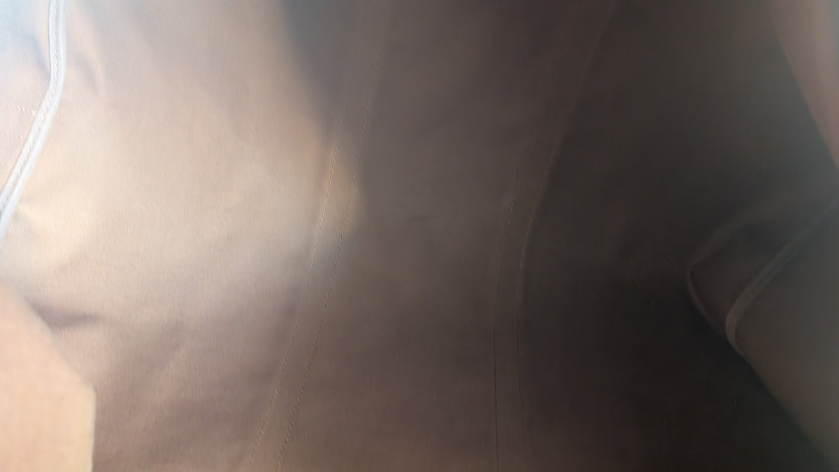 A close-up, low-resolution view of a beige or light brown textured fabric surface with a white piping detail on the left side. Pre-Owned Louis Vuitton Keepall Bandoulière 60 Monogram Travel Bag