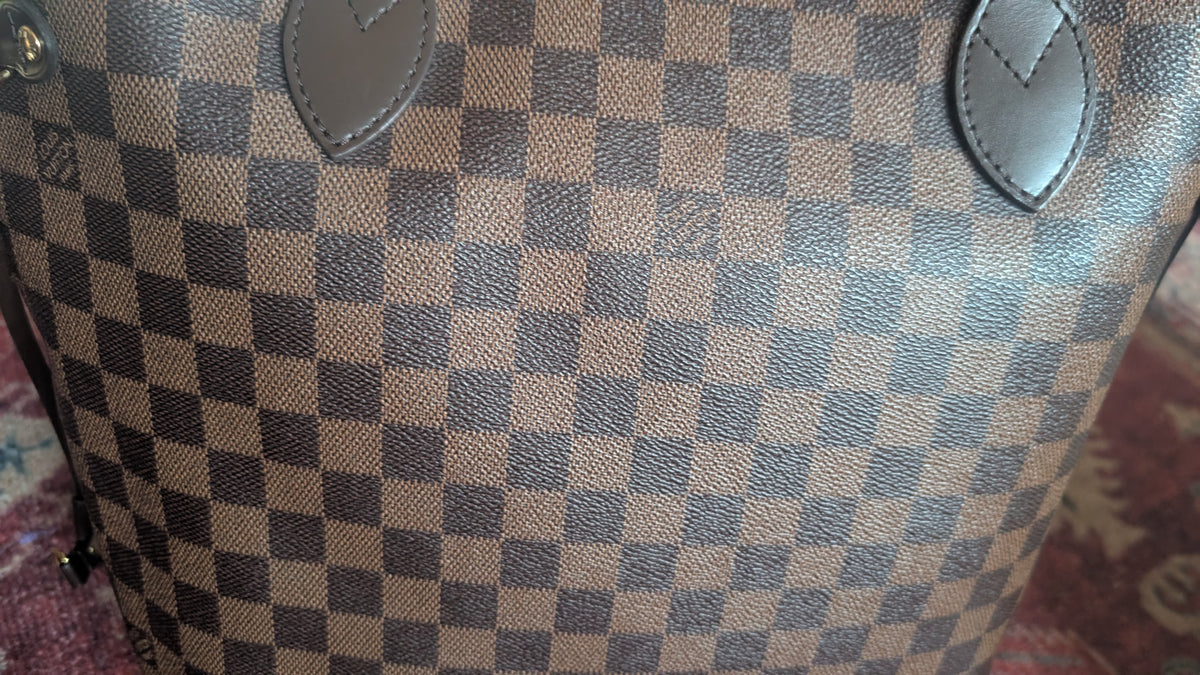 Close-up of a Louis Vuitton handbag in Damier Ebene canvas, showing the brown and beige checkered pattern with dark brown leather trim. Pre-Owned Louis Vuitton Neverfull MM Damier Ebene, Cerise Red