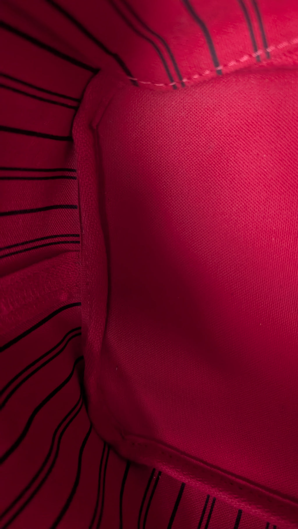 Close-up of a bright pink fabric surface with black pinstripes along the edges and a stitched seam visible. Pre-Owned Louis Vuitton Neverfull MM Damier Ebene, Cerise Red