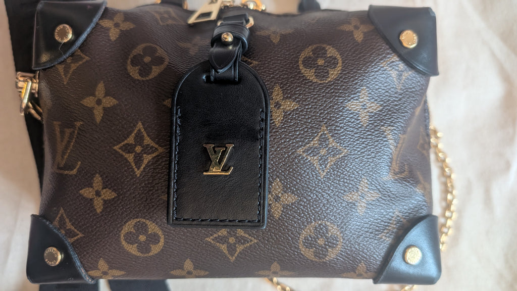 A Louis Vuitton monogram canvas shoulder bag in dark brown with gold-tone hardware, featuring a black leather luggage tag with a gold LV logo. Pre-Owned Louis Vuitton Petite Malle Souple Monogram Bag