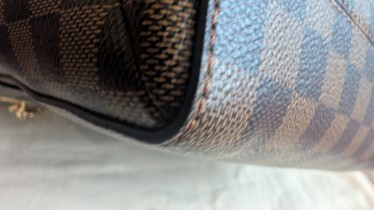 Close-up of a handbag corner showing the Damier Azur canvas pattern with brown, beige, and blue-gray checkers, black leather trim, and gold-tone stitching. Pre-Owned Louis Vuitton Vavin PM Damier Ebene / Crème – N40113