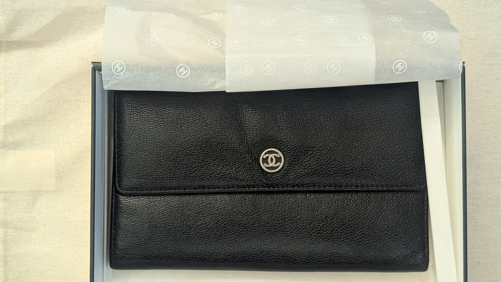 A black textured leather Chanel card holder with a silver-tone interlocking CC logo, presented inside its white box with branded tissue paper. Pre-Owned Chanel Vintage Black Caviar Leather Wallet with Added Chain