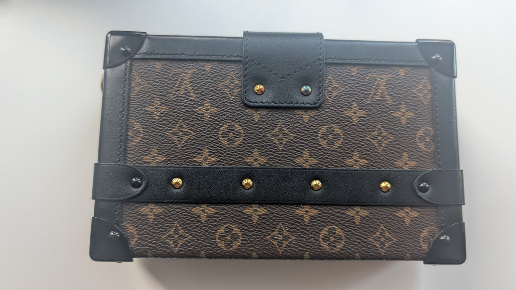A Louis Vuitton monogram canvas notebook or journal with dark brown leather trim, corner protectors, and gold-tone metal rivets, shown on a plain light background. Pre-Owned Louis Vuitton Petite Malle Monogram Canvas Crossbody Bag