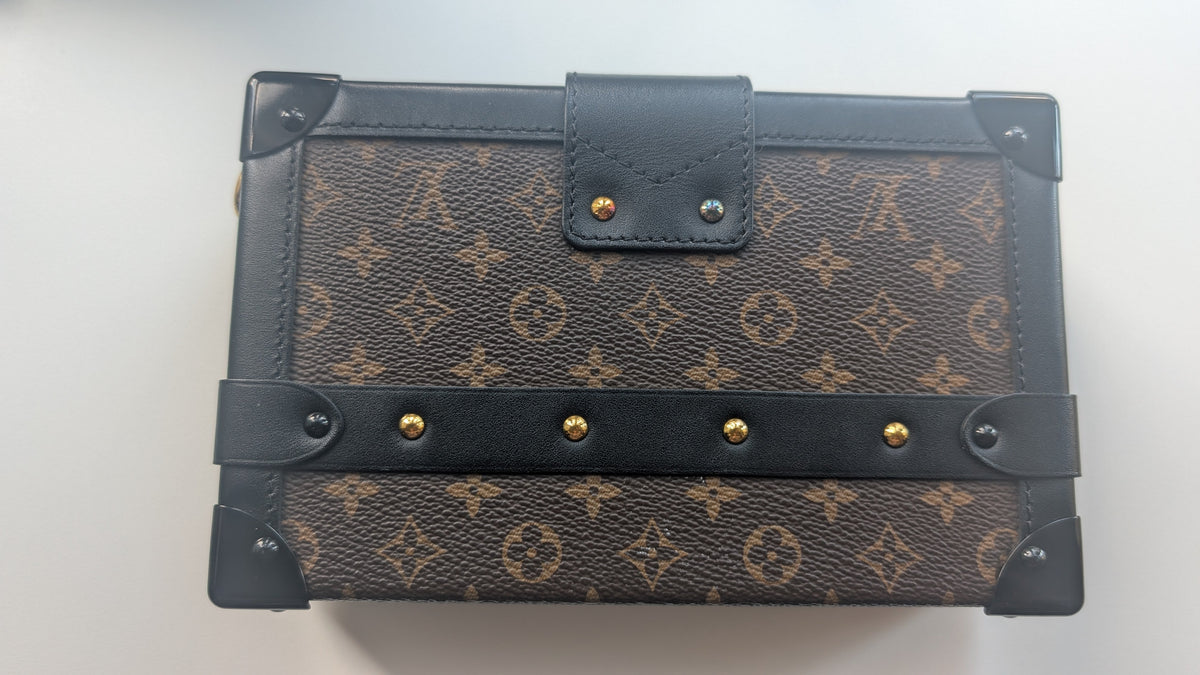 A Louis Vuitton monogram canvas notebook or journal with dark brown leather trim, corner protectors, and gold-tone metal rivets, shown on a plain light background. Pre-Owned Louis Vuitton Petite Malle Monogram Canvas Crossbody Bag