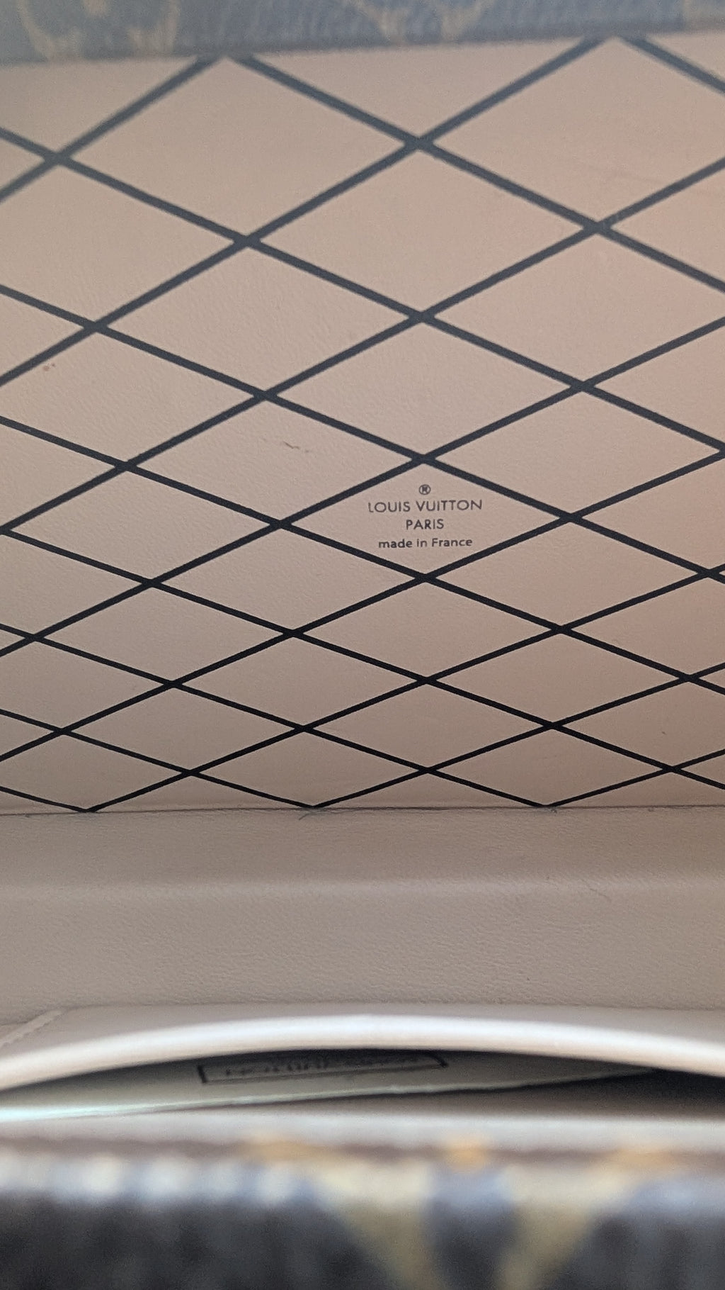 Close-up of a Louis Vuitton handbag interior showing the signature diamond pattern in beige and black, with the Louis Vuitton Paris logo printed in the center. Pre-Owned Louis Vuitton Petite Malle Monogram Canvas Crossbody Bag