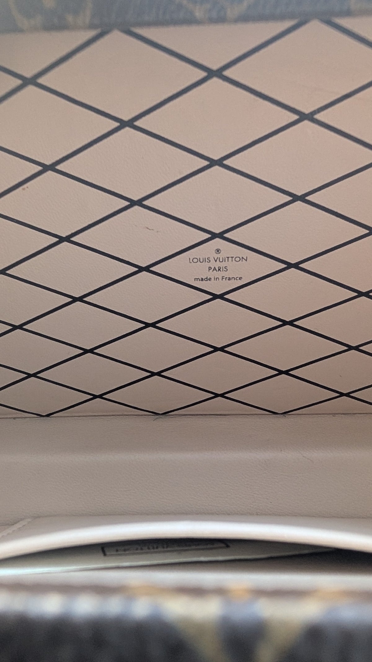 Close-up of a Louis Vuitton handbag interior showing the signature diamond pattern in beige and black, with the Louis Vuitton Paris logo printed in the center. Pre-Owned Louis Vuitton Petite Malle Monogram Canvas Crossbody Bag
