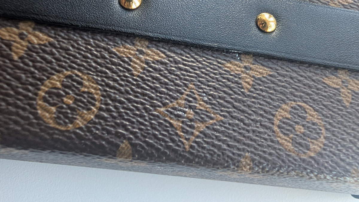 Close-up of a Louis Vuitton monogram canvas bag with dark brown coated canvas, tan monogram print, and a black leather trim with gold-tone rivets. Pre-Owned Louis Vuitton Petite Malle Monogram Canvas Crossbody Bag