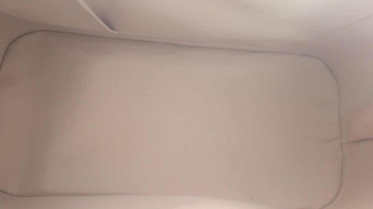 Close-up view of a plain light beige fabric interior or pouch lining with stitched edges and a small loop at the  Pre-Owned Louis Vuitton Alma PM Monogram Vernis – Beige Poudretop.