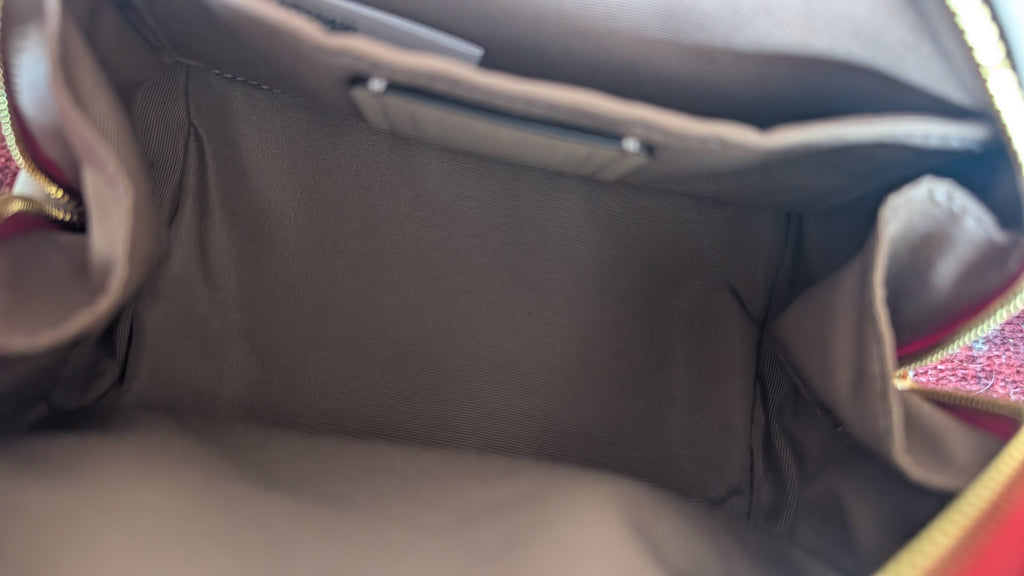 Close-up view of the interior lining of a handbag, showing a gray fabric compartment with a zippered pocket and side pockets. Pre-Owned Coach Sydney Satchel With Heart Cherry Print – CF421
