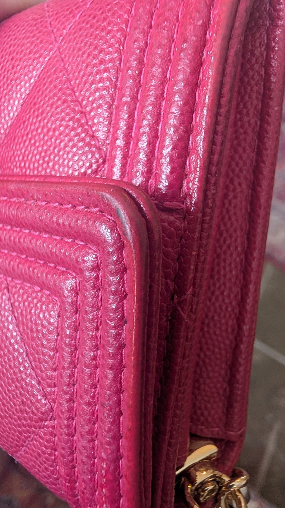 A close-up of a bright pink textured leather handbag corner with visible gold-tone hardware. Pre-Owned Chanel Boy Wallet on Chain – Fuchsia Pink Caviar Leather – Gold Hardware