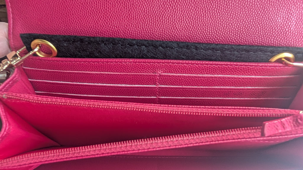 Close-up of a bright pink pebbled leather handbag interior showing card slots, a black fabric divider, gold-tone hardware, and a zipper compartment. Pre-Owned Chanel Boy Wallet on Chain – Fuchsia Pink Caviar Leather – Gold Hardware