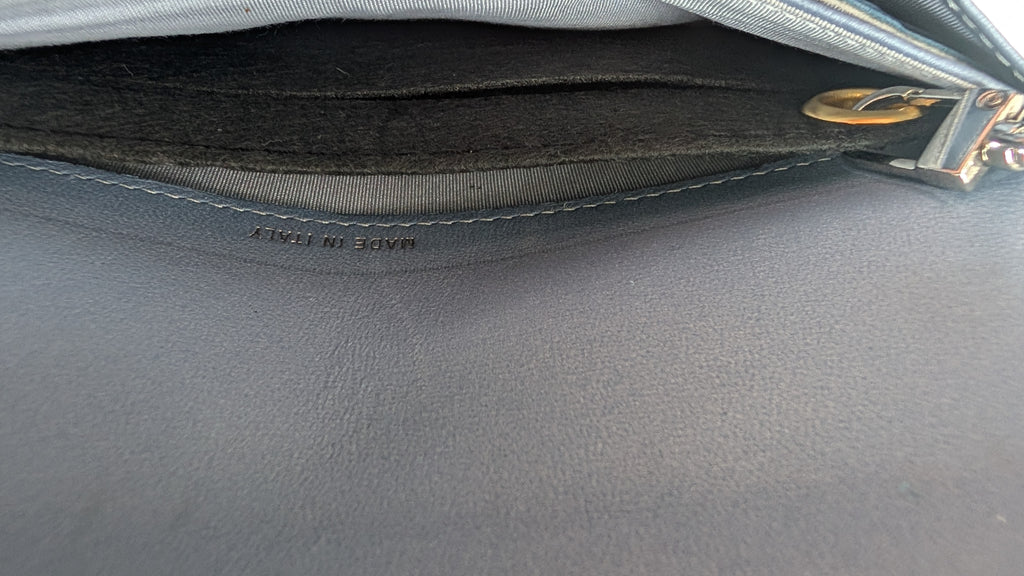 Close-up detail of a dark gray leather zippered pouch or clutch, showing the interior lining, a gold-tone zipper pull, and 'MADE IN ITALY' embossed on the leather edge. Pre-Owned Chanel Camellia Studded Wallet on Chain WOC – Blue Lambskin
