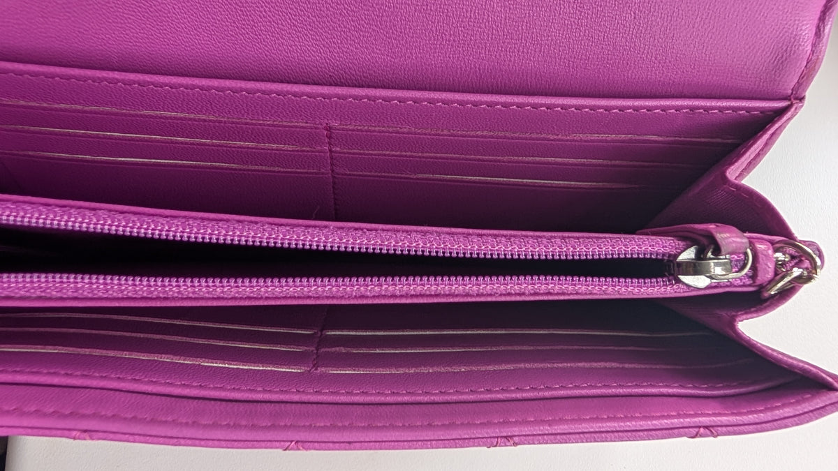Close-up of the interior of a magenta purple leather wallet or card holder, showing multiple card slots, a zippered compartment, and silver zipper hardware. Pre-Owned Chanel Quilted Wallet on Chain WOC – Pink/Purple Lambskin – Silver Hardware
