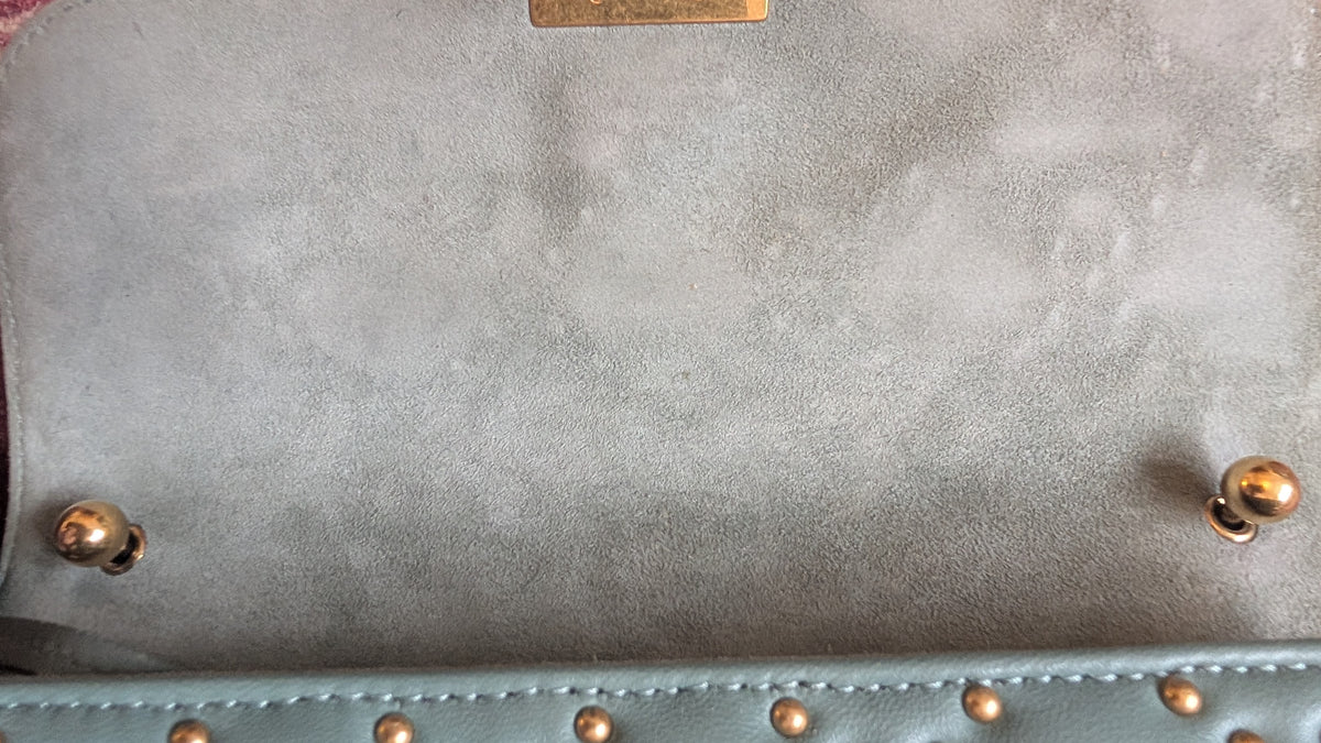 Close-up of a light blue suede or nubuck handbag interior with gold-tone studs and hardware. Pre-Owned Christian Dior Small DiorAddict Cannage Studded Flap Bag – Light Blue Lambskin