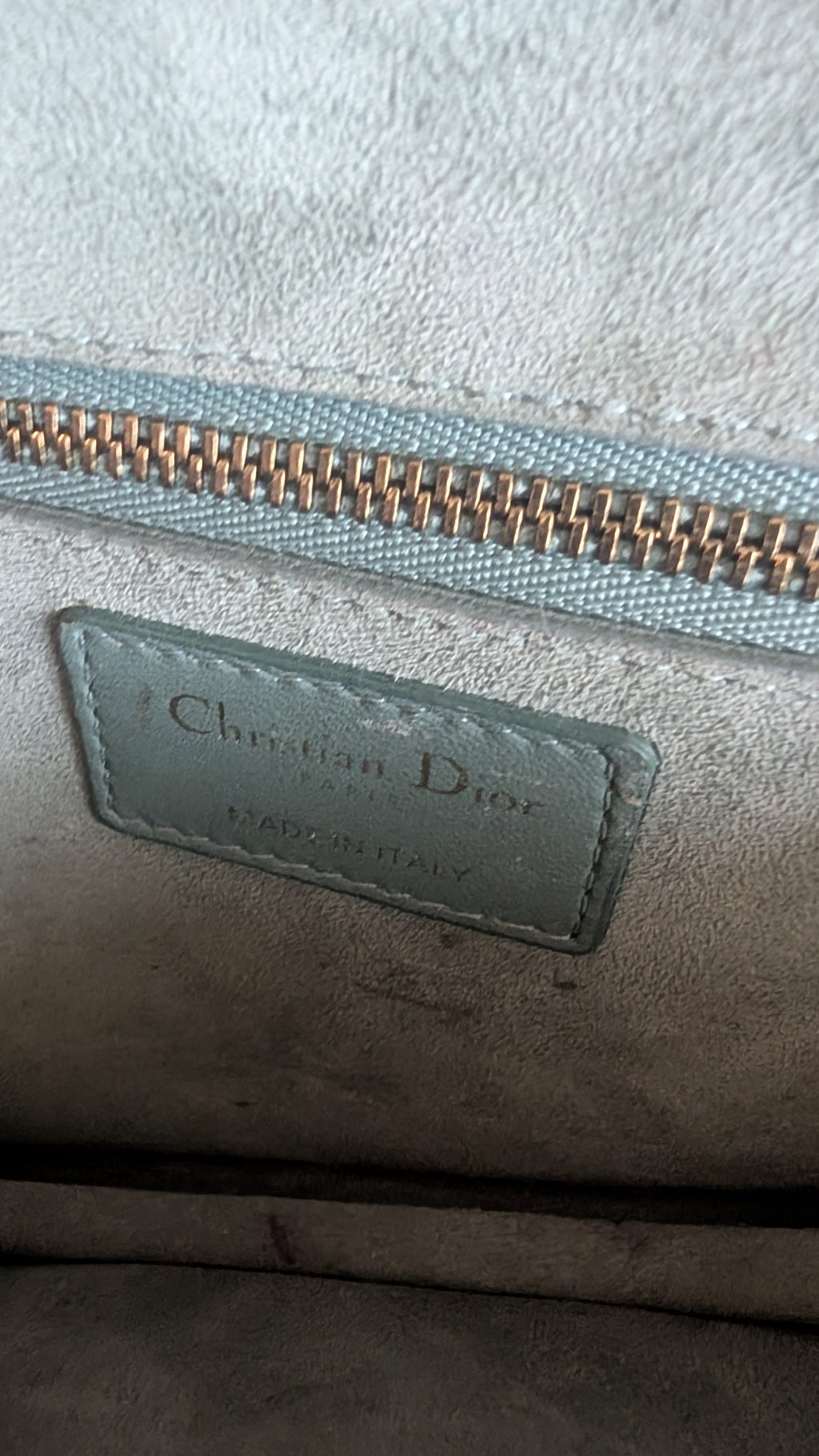 Close-up of a Christian Dior handbag interior showing a light blue suede-like lining, a gold zipper, and a stitched Christian Dior label. Pre-Owned Christian Dior Small DiorAddict Cannage Studded Flap Bag – Light Blue Lambskin