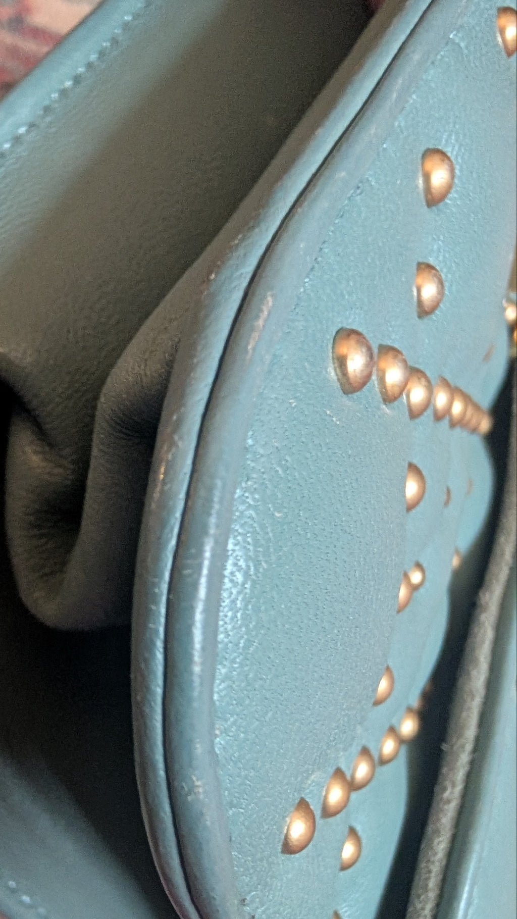 Close-up of a light blue leather clutch or wallet with gold-tone studs, showing the interior lining and texture. Pre-Owned Christian Dior Small DiorAddict Cannage Studded Flap Bag – Light Blue Lambskin